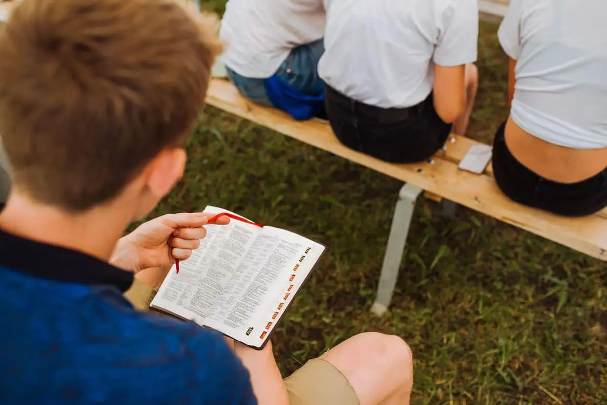 A young man reading the Bible on the grass