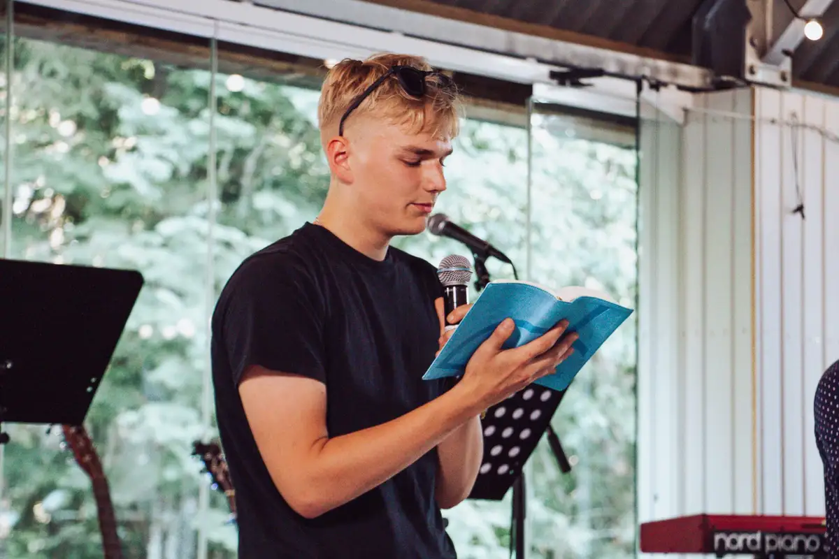 A young man reads the Bible at the microphone