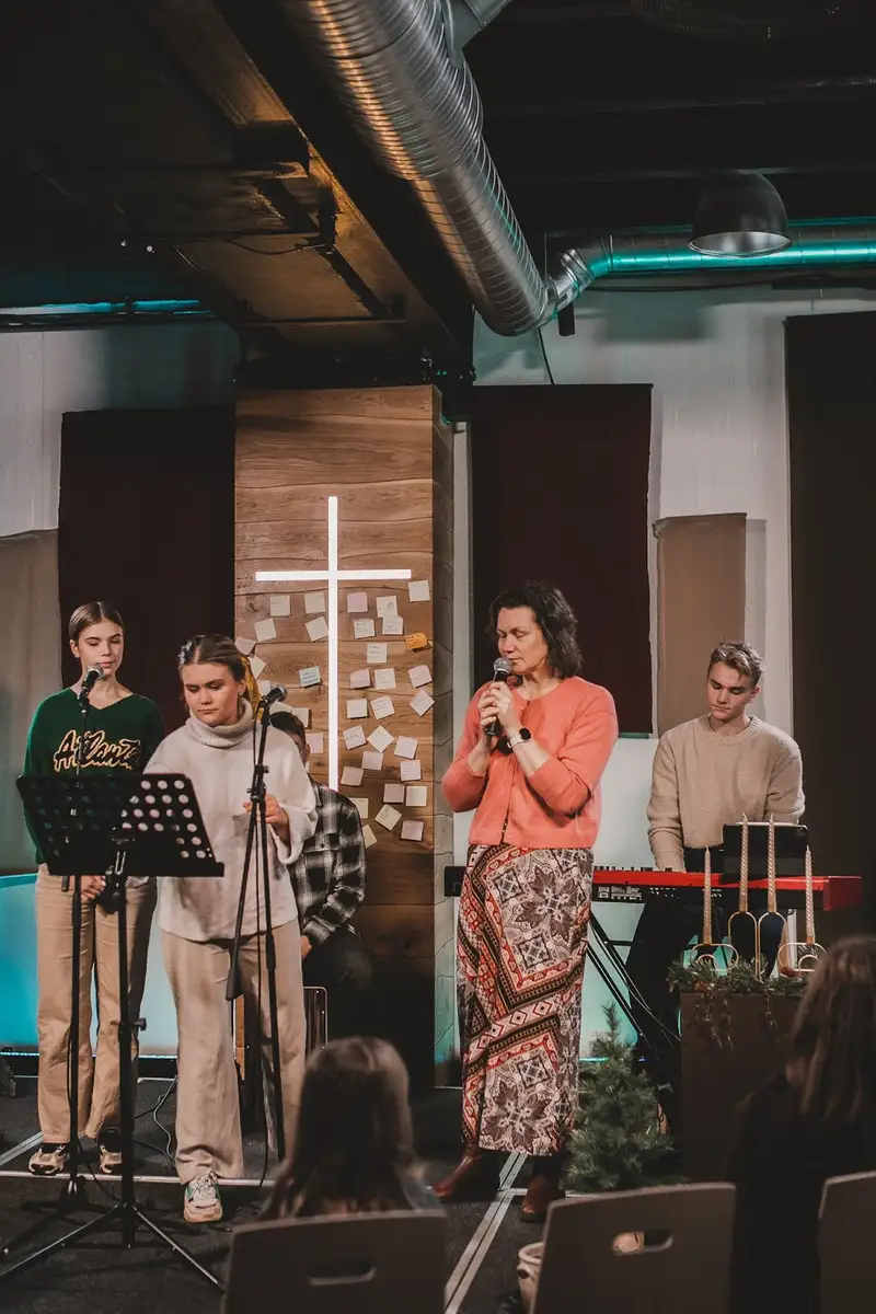 The wooden wall, the white cross and the singers